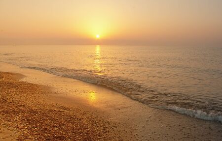 beautiful sunset and waves on the beach の写真素材