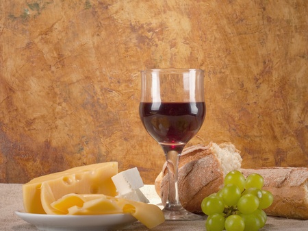 Red wine, assorted cheeses, bread and grapes in a still life setup. の写真素材