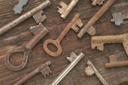 Antique steel keys on old wooden background の写真素材