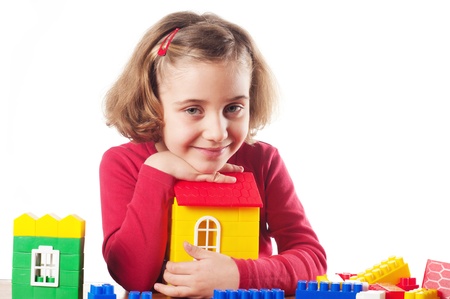 Cute little girl is constructing a house using building blocks の写真素材
