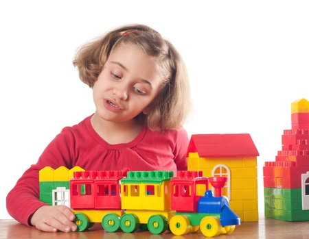 Cute little girl is constructing a house using building blocks の写真素材