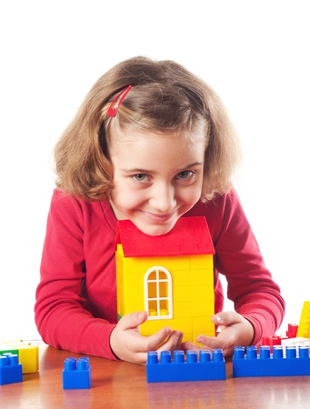 Cute little girl is constructing a house using building blocks の写真素材