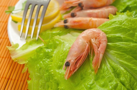 many raw shrimp with lemon on lettuce leaves on a plate の写真素材