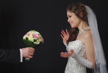Beautiful bride with wedding bouquet on a dark background の写真素材