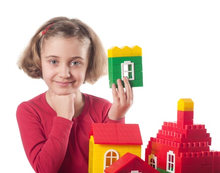 Cute little girl is constructing a house using building blocks の写真素材