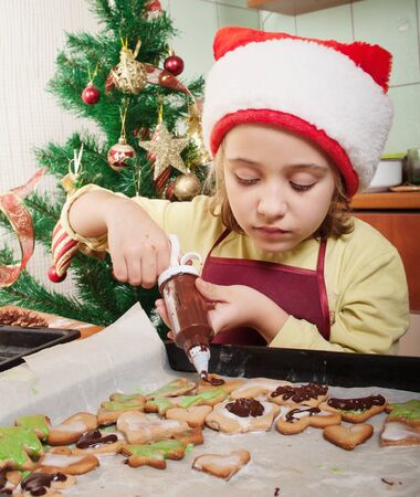 Little girl decorating the christmas cookies の写真素材