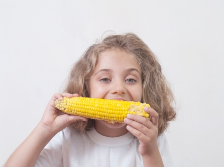 Young funny girl eating a boiled corn の写真素材
