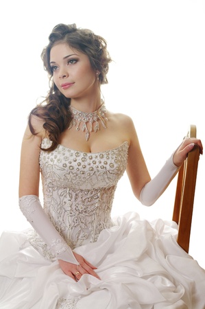 beautiful girl in wedding dress on the chair isolated on white の写真素材