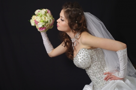 Beautiful bride with wedding bouquet on a dark backgroundの写真素材