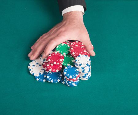 hands rakes the pile of poker chipsの写真素材