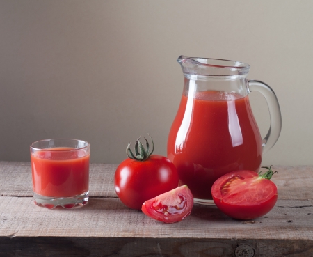jar with tomato juice and tomatoes on a wooden tableの写真素材