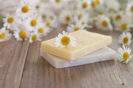 Bar of natural handmade soap and chamomile on wooden background. Selective focus.の写真素材