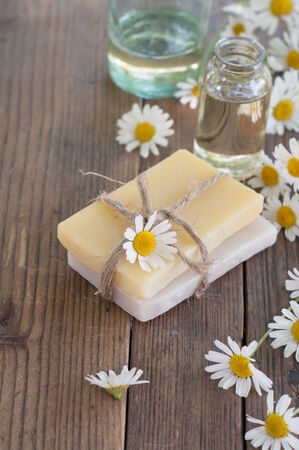 Bar of natural handmade soap and chamomile on wooden background. Selective focus.の写真素材