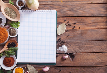 notebook with spices and herbs on the old wooden cutting boardの写真素材