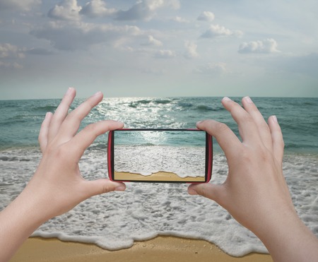 Hands taking photo beach with smartphone