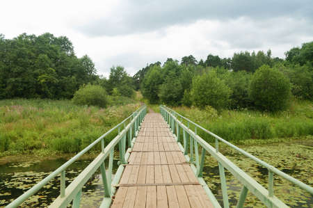 landscape with a wooden bridge over the riverの写真素材