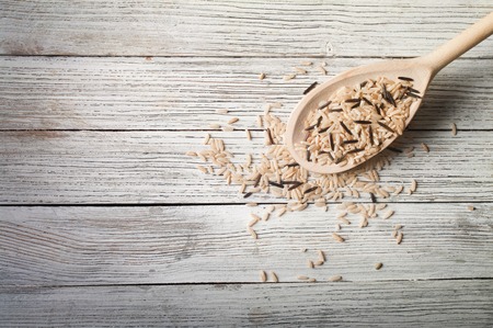 Rice with wooden spoon on wooden tableの写真素材