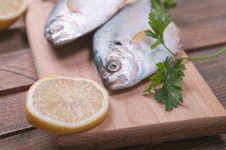 Delicious fresh sea bream fish on wooden kitchen boardの写真素材
