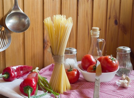 Pasta, tomatoes, onion, olive oil and basil on wooden backgroundの写真素材