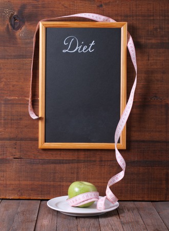 Black chalkboard for menu and apple over wooden background. Diet food concept.の写真素材