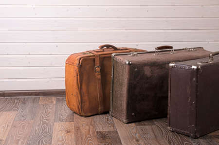 Vintage leather suitcase on white wall.