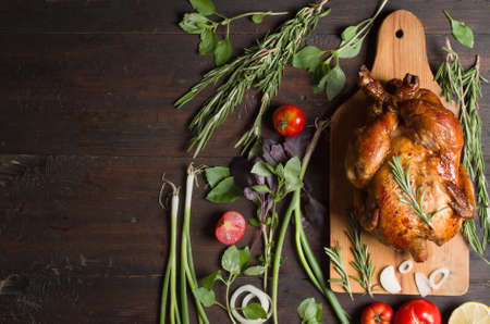 Whole roasted chicken with vegetables, on wooden tableの写真素材
