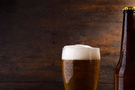 bottle and glass with beer on wood table