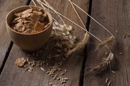Wheat corn and oat flakes on a wooden tableの写真素材