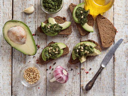 Sandwich with pesto sauce and avocado on a wooden board