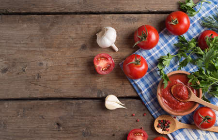Ketchup and ingredients on wood background