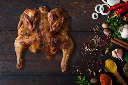 cooked chicken on a wooden table and spicesの写真素材