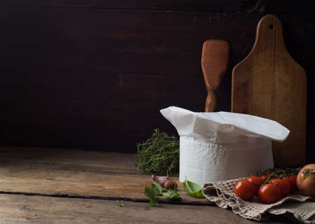 Chef's hat on an old wooden table. Conceptual background on the theme of food.の写真素材