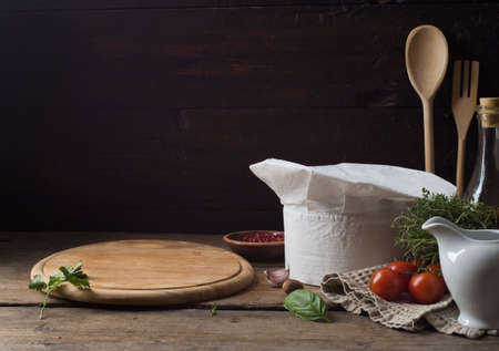 Chef's hat on an old wooden table. Conceptual background on the theme of food.の写真素材