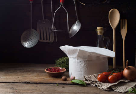 Chef's hat on an old wooden table. Conceptual background on the theme of food.の写真素材