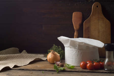 Chef's hat on an old wooden table. Conceptual background on the theme of food.の写真素材