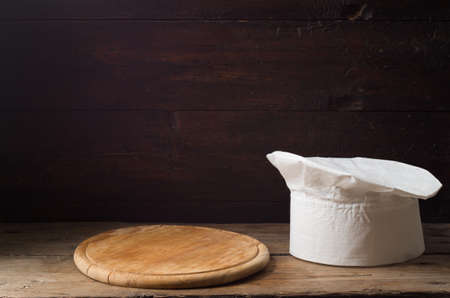 Chef's hat on an old wooden table. Conceptual background on the theme of food.の写真素材