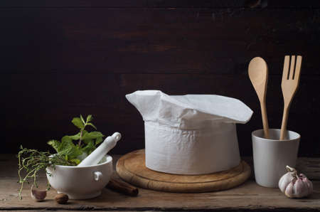 Chef's hat on an old wooden table. Conceptual background on the theme of food.の写真素材