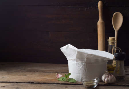 Chef's hat on an old wooden table. Conceptual background on the theme of food.の写真素材