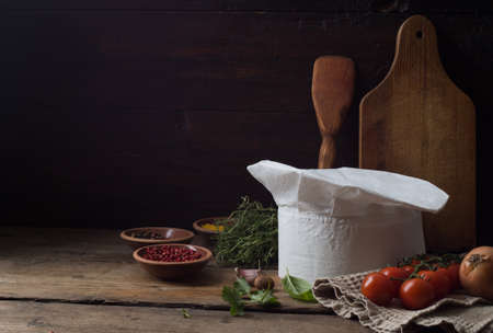 Chef's hat on an old wooden table. Conceptual background on the theme of food.の写真素材