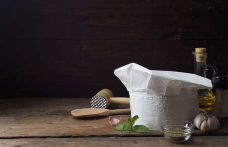 Chef's hat on an old wooden table. Conceptual background on the theme of food.の写真素材