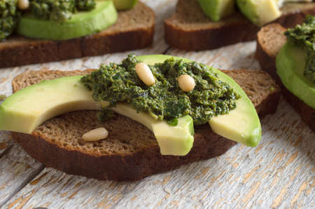 Sandwich with pesto sauce and avocado on a wooden boardの写真素材