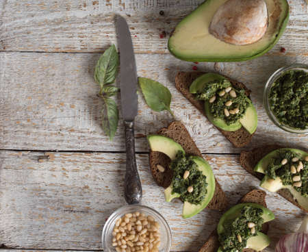 Sandwich with pesto sauce and avocado on a wooden boardの写真素材