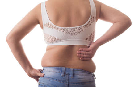 Fat woman isolated over white clings to a sick fat backの写真素材