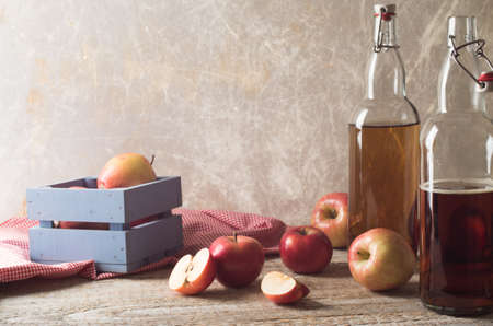 Cider with apples and bottle on rustic wooden backgroundの写真素材