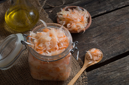 Sour cabbage fermented sauerkraut with carrot in a old wooden tableの写真素材