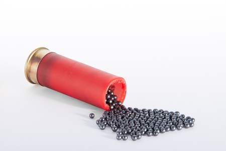 A shotgun red cartridge in horizontal position, open at the top  and the pellets drop out. Isolated...