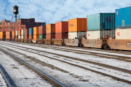 Industrial railway terminal in winter with container transport wagons, rails, old brick building,...