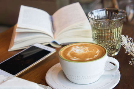 coffee cup and tasty cake relax time book and mobile phone on table in coffee shopの写真素材