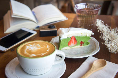 coffee cup and tasty cake relax time book and mobile phone on table in coffee shopの写真素材
