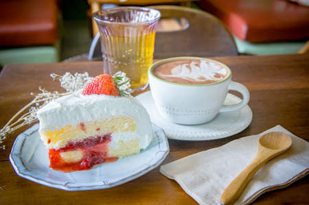 coffee cup and delicious cake strawberry and relax time moblie on table in coffee shopの写真素材